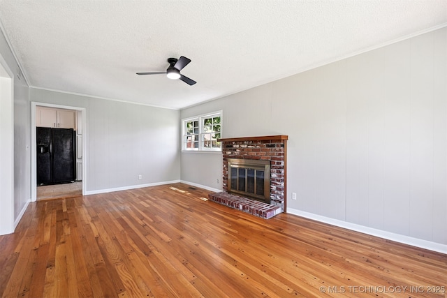 4643 E 59th St, Tulsa, OK 74135 - unfurnished living room featuring wood-type flooring, a fireplace, ceiling fan, crown molding, and a textured ceiling