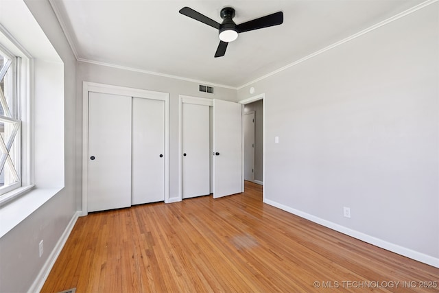 4643 E 59th St, Tulsa, OK 74135 - unfurnished bedroom featuring light wood finished floors, multiple closets, ornamental molding, and ceiling fan