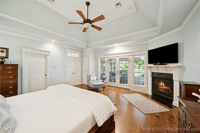 8002 E Galveston Pl, Broken Arrow, OK 74014 - bedroom featuring wood finished floors, a tiled fireplace, a raised ceiling, access to exterior, and ornamental molding