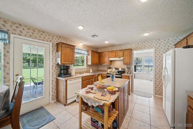 5621 E Hunter Ln, Claremore, OK 74019 - kitchen featuring white appliances, wallpapered walls, under cabinet range hood, light countertops, and plenty of natural light