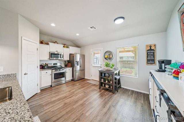 1111 W Cheyenne Ln, Claremore, OK 74019 - kitchen featuring appliances with stainless steel finishes, light wood-type flooring, white cabinets, lofted ceiling, and light stone countertops