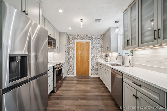 1120 S Sequoyah Dr, Oologah, OK 74053 - kitchen with stainless steel appliances, light countertops, dark wood finished floors, glass insert cabinets, and wallpapered walls