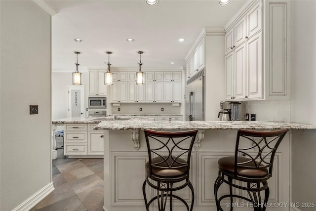 5428 E 88th St, Tulsa, OK 74137 - kitchen featuring built in appliances, a peninsula, recessed lighting, light stone counters, and a breakfast bar