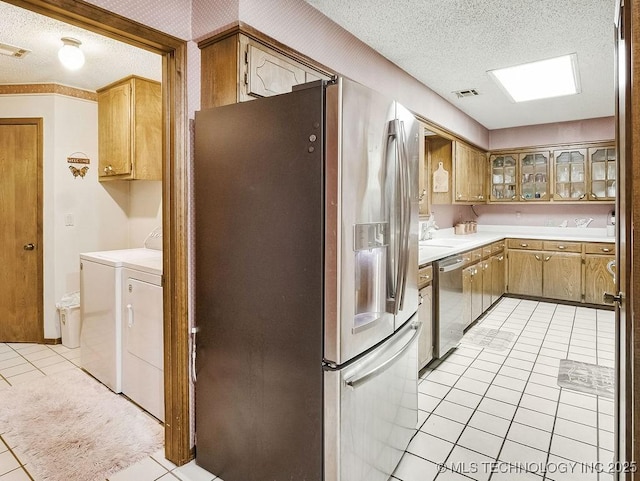 301 S Byrd, Coalgate, OK 74538 - kitchen featuring appliances with stainless steel finishes, separate washer and dryer, light tile patterned floors, a textured ceiling, and light countertops