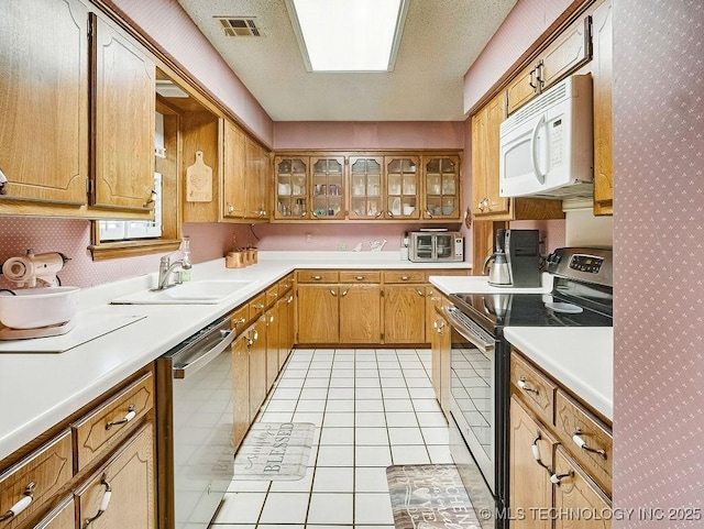 301 S Byrd, Coalgate, OK 74538 - kitchen with stainless steel appliances, light countertops, glass insert cabinets, brown cabinets, and wallpapered walls
