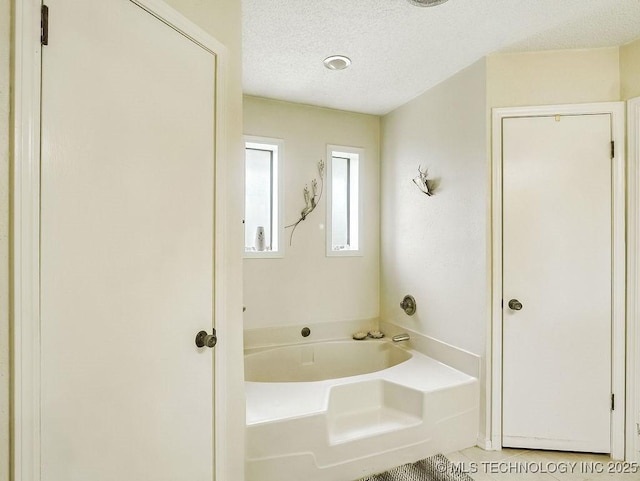 301 S Byrd, Coalgate, OK 74538 - bathroom featuring a garden tub, a textured ceiling, and tile patterned flooring