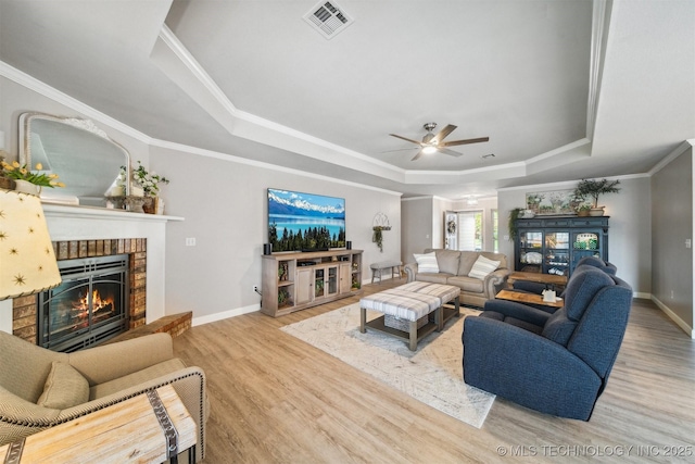 12708 E 78th St, Owasso, OK 74055 - living room with a tray ceiling, a fireplace, wood finished floors, ceiling fan, and crown molding