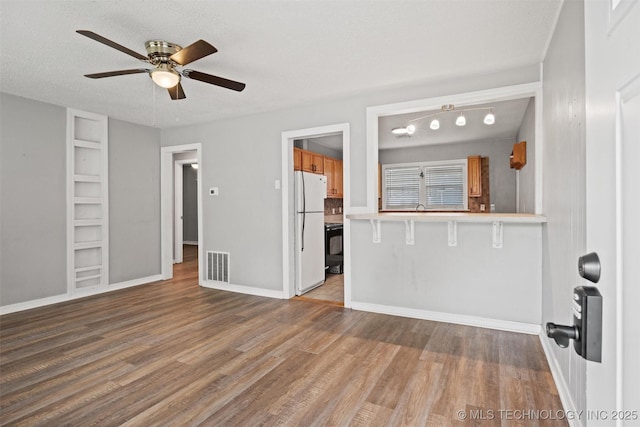 345 N Pine, Dewey, OK 74029 - unfurnished living room with a ceiling fan, wood finished floors, built in shelves, and a textured ceiling