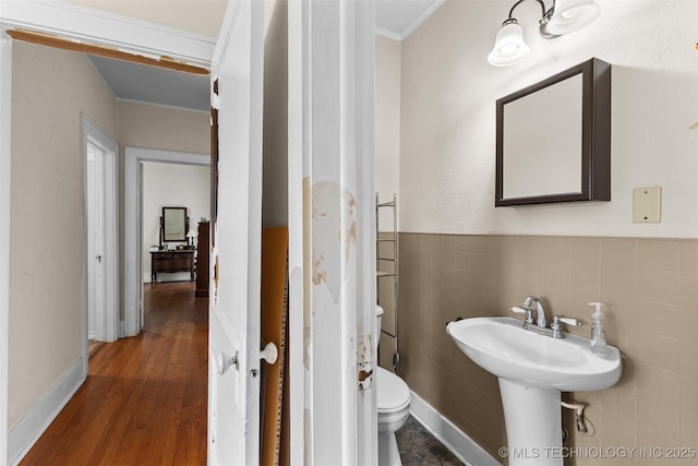 817 S Stockton, Ada, OK 74820 - half bathroom featuring crown molding, wood finished floors, tile walls, and wainscoting