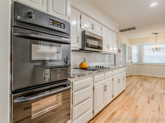 5610 S 75th E Pl, Tulsa, OK 74145 - kitchen with black appliances, a chandelier, white cabinetry, and light wood-style floors