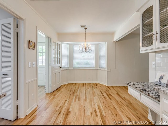 5610 S 75th E Pl, Tulsa, OK 74145 - unfurnished dining area with light wood finished floors, a chandelier, and a decorative wall
