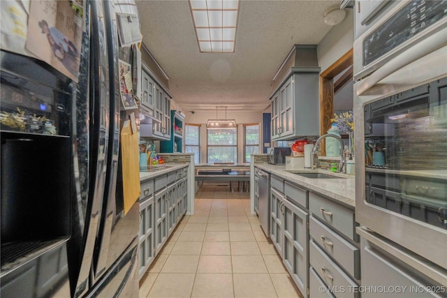 920 Ridge Oak Rd, Sapulpa, OK 74066 - kitchen featuring gray cabinets, a textured ceiling, light tile patterned floors, and freestanding refrigerator