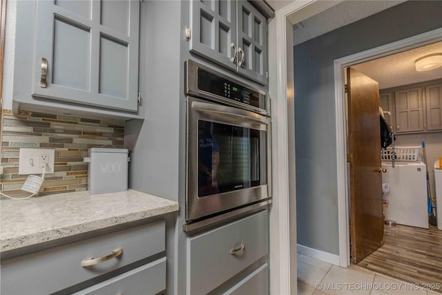 920 Ridge Oak Rd, Sapulpa, OK 74066 - kitchen with oven, backsplash, gray cabinetry, light tile patterned floors, and light stone counters