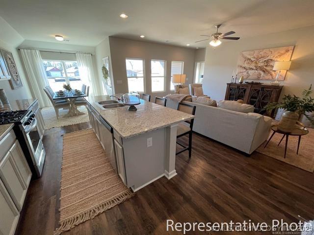 8308 E Oakland St, Broken Arrow, OK 74014 - kitchen with stainless steel gas stove, dark wood-type flooring, a breakfast bar, an island with sink, and recessed lighting