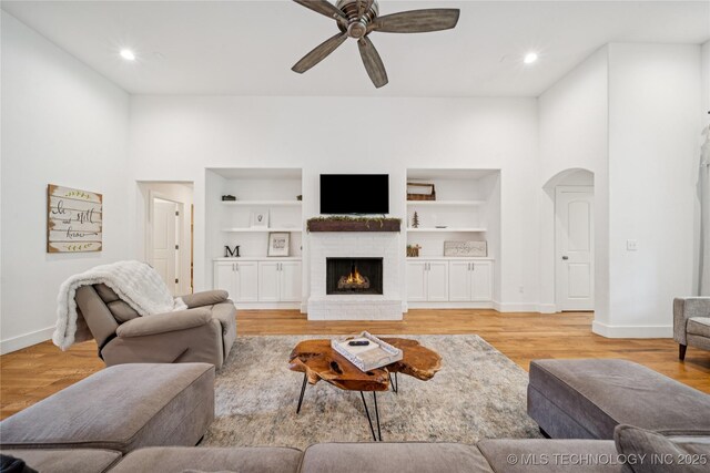 7383 S 288th E Ave, Broken Arrow, OK 74014 - living room featuring a ceiling fan, arched walkways, light wood-style flooring, a brick fireplace, and built in features