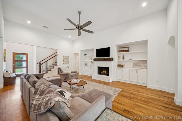 7383 S 288th E Ave, Broken Arrow, OK 74014 - living area featuring stairs, ceiling fan, a brick fireplace, light wood-type flooring, and built in shelves