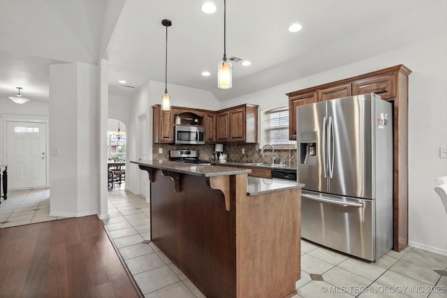 7316 E Knoxville St, Broken Arrow, OK 74014 - kitchen featuring appliances with stainless steel finishes, a breakfast bar, tasteful backsplash, dark stone countertops, and decorative light fixtures