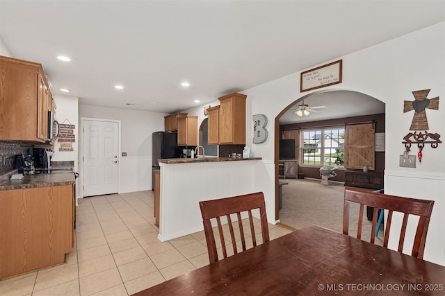 24 Faye Ave, Inola, OK 74036 - kitchen with arched walkways, a ceiling fan, light tile patterned floors, dark countertops, and open floor plan