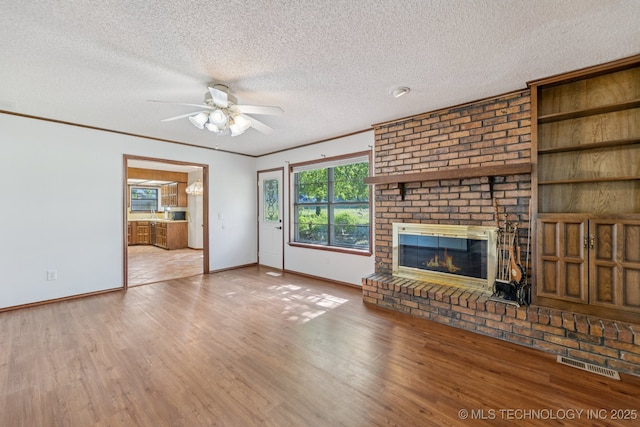 10421 S 197th E Ave, Broken Arrow, OK 74014 - unfurnished living room featuring ceiling fan, a fireplace, a textured ceiling, and wood finished floors