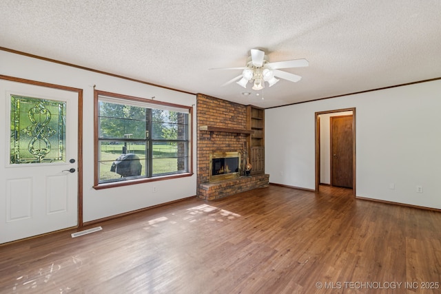 10421 S 197th E Ave, Broken Arrow, OK 74014 - unfurnished living room featuring a textured ceiling, a ceiling fan, wood finished floors, crown molding, and a fireplace