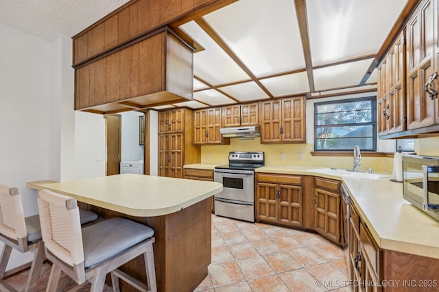 10421 S 197th E Ave, Broken Arrow, OK 74014 - kitchen with light countertops, appliances with stainless steel finishes, brown cabinetry, a breakfast bar, and under cabinet range hood