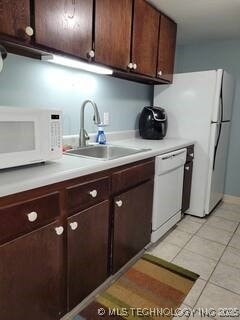 450 W 7th St Unit 704, Tulsa, OK 74119 - kitchen featuring white appliances, light countertops, light tile patterned floors, and dark brown cabinetry