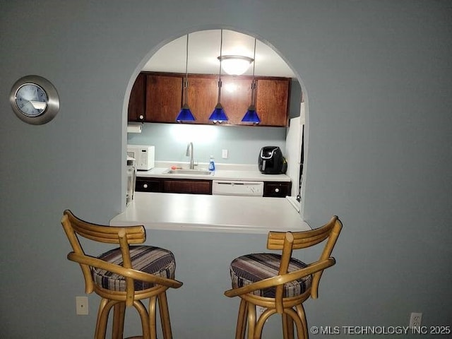 450 W 7th St Unit 704, Tulsa, OK 74119 - kitchen with arched walkways, a kitchen breakfast bar, white appliances, light countertops, and a peninsula