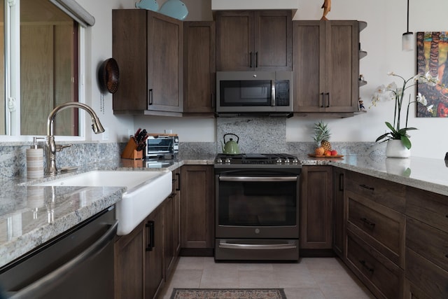 kitchen with light stone countertops, stainless steel appliances, and light tile patterned floors