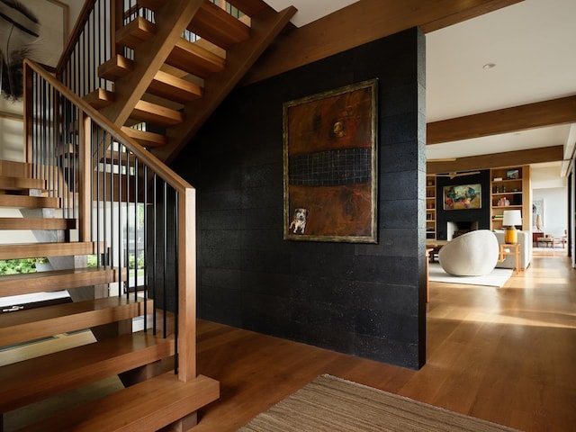 stairway with hardwood / wood-style floors and built in shelves