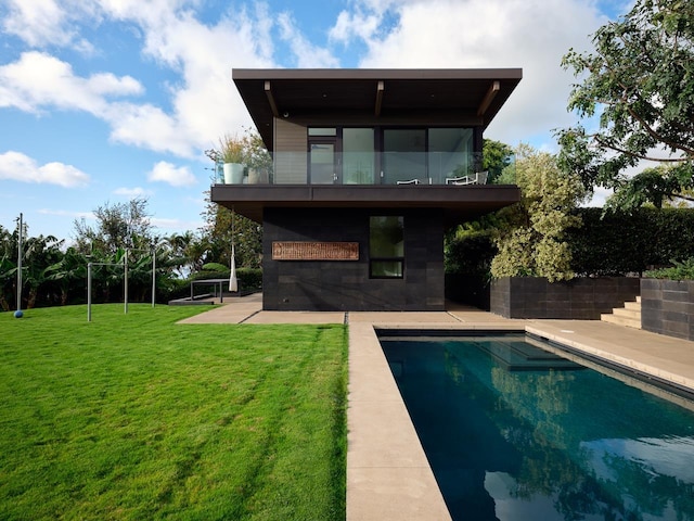 rear view of house with a fenced in pool, a patio area, and a yard