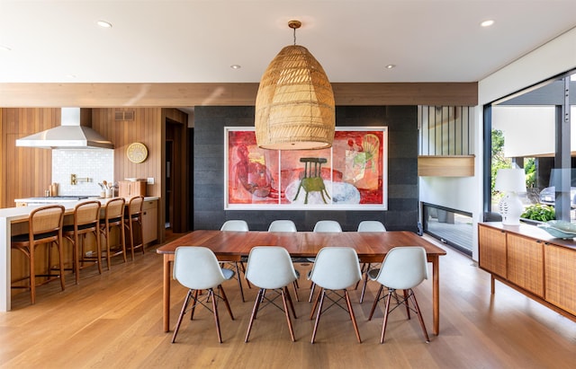 dining room with light wood-type flooring and a tiled fireplace