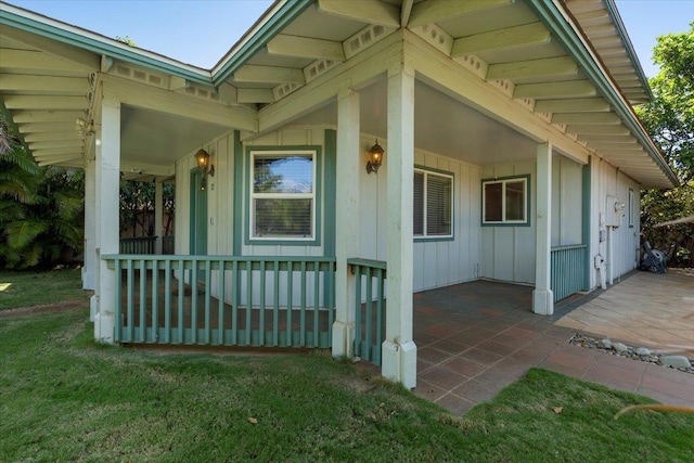 property entrance featuring a yard, covered porch, and board and batten siding