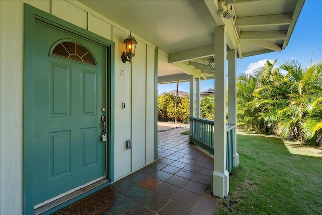 view of exterior entry featuring a yard and a porch