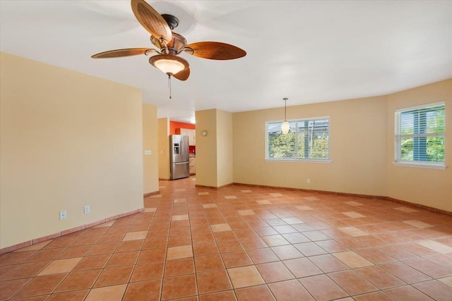 empty room featuring light tile patterned flooring, plenty of natural light, baseboards, and a ceiling fan