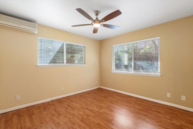 empty room featuring a wealth of natural light, baseboards, a ceiling fan, and a wall mounted AC