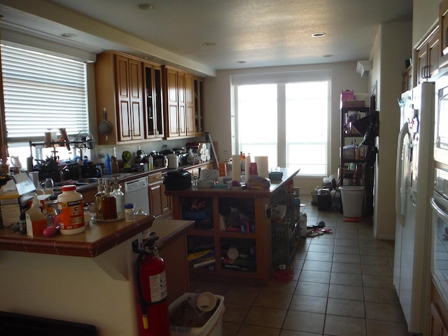 kitchen featuring tile countertops, tile patterned flooring, and white appliances