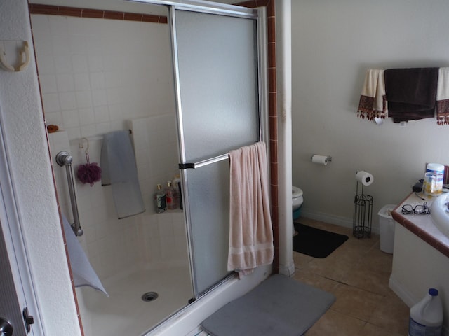 bathroom featuring tile patterned floors, toilet, and a shower with shower door