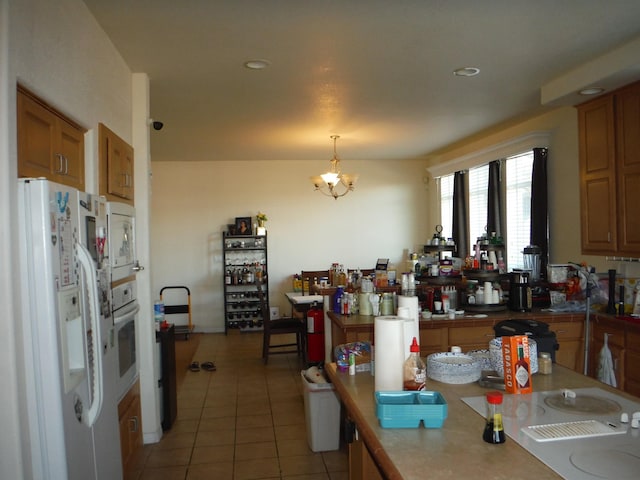 kitchen featuring light tile patterned floors, decorative light fixtures, white appliances, and an inviting chandelier