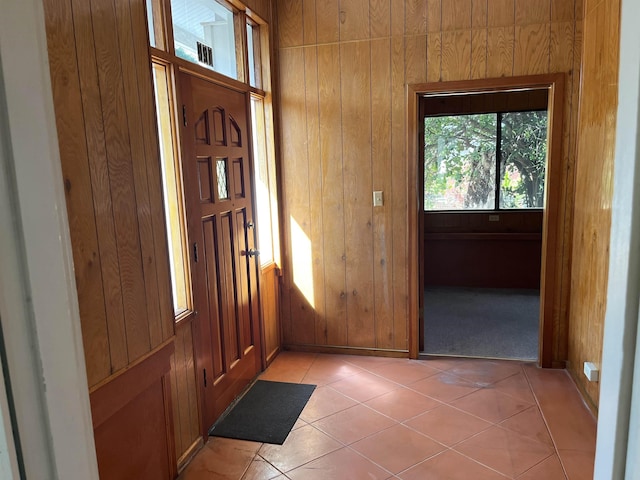 entrance foyer with light tile patterned floors and wood walls