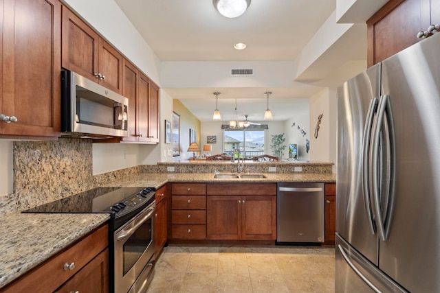28 Hauwahine Ln Unit F203, Kihei, HI 96753 - kitchen featuring appliances with stainless steel finishes, brown cabinetry, decorative light fixtures, light stone countertops, and a peninsula