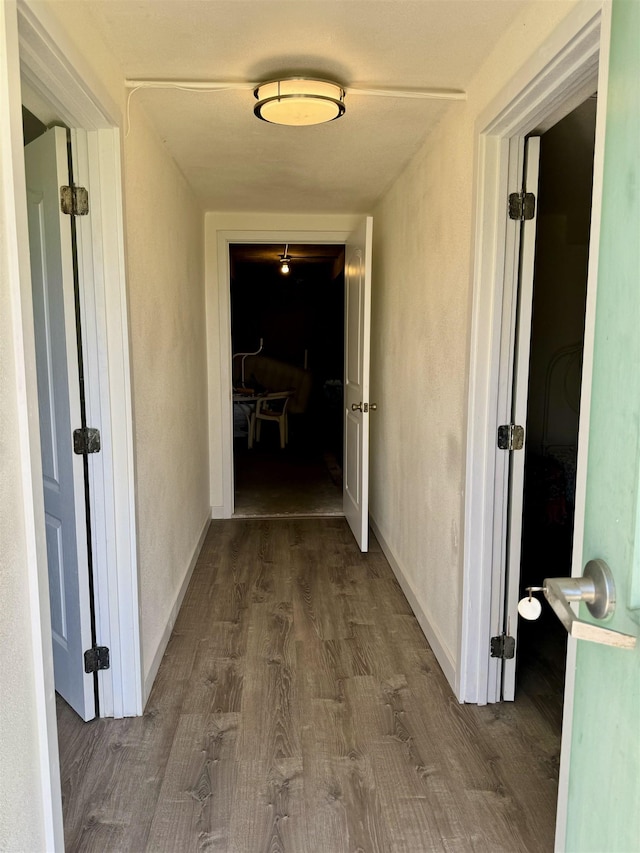 hall with dark wood-style floors and baseboards
