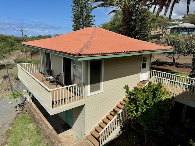 back of property featuring a tiled roof and stairway