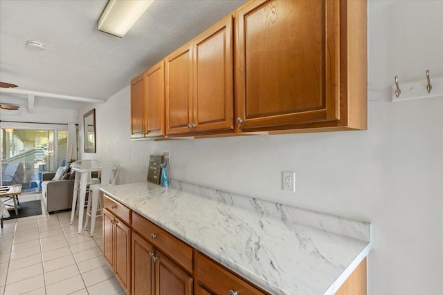 kitchen featuring light stone countertops, light tile patterned floors, and beam ceiling