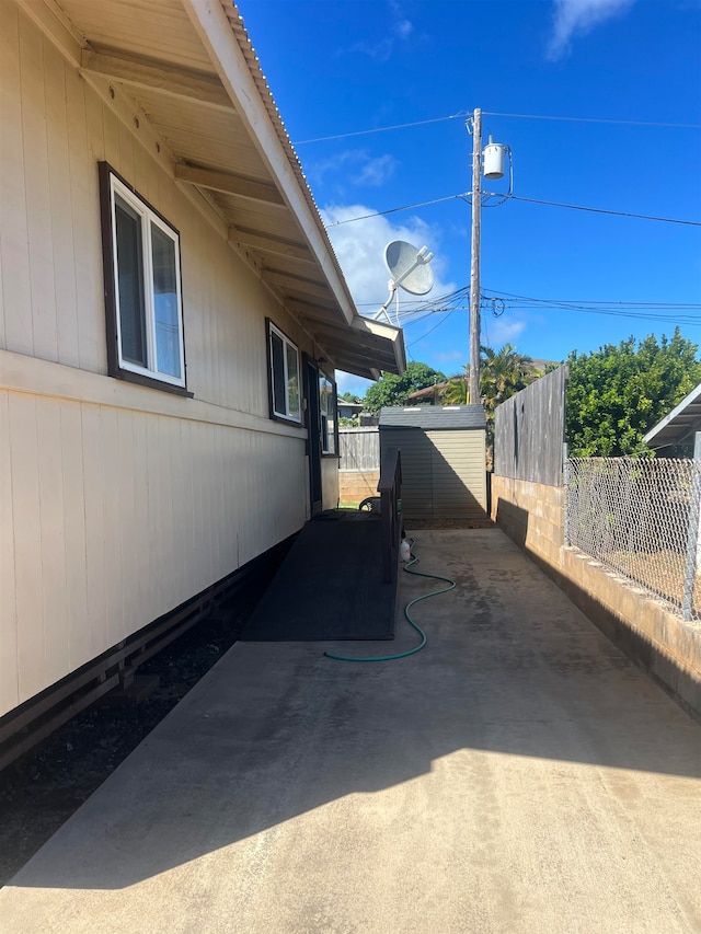 view of home's exterior with a patio area and a storage shed