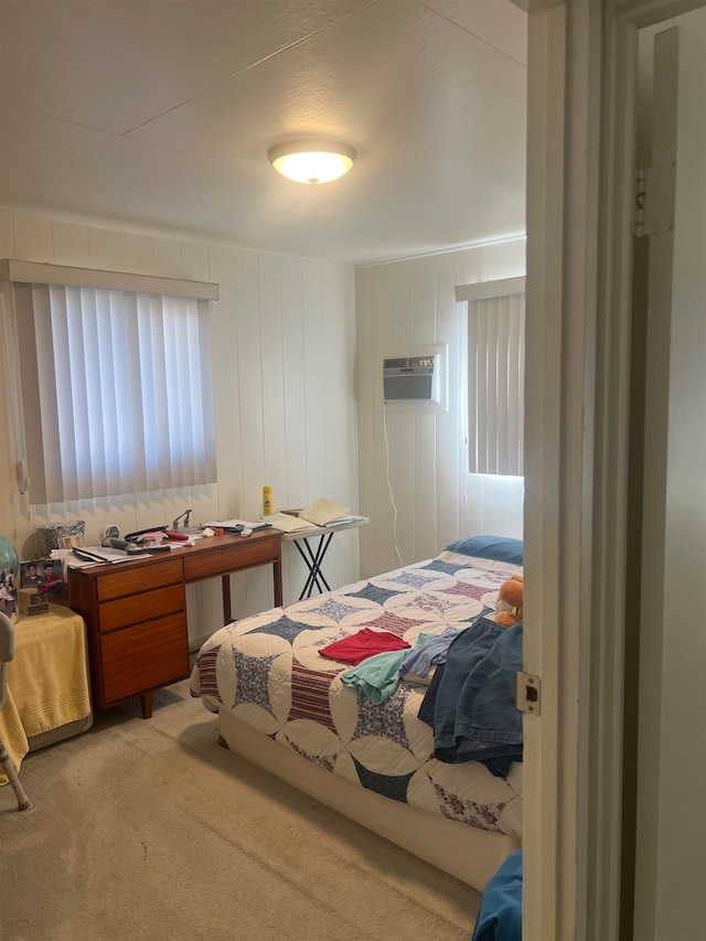 carpeted bedroom featuring wood walls and an AC wall unit