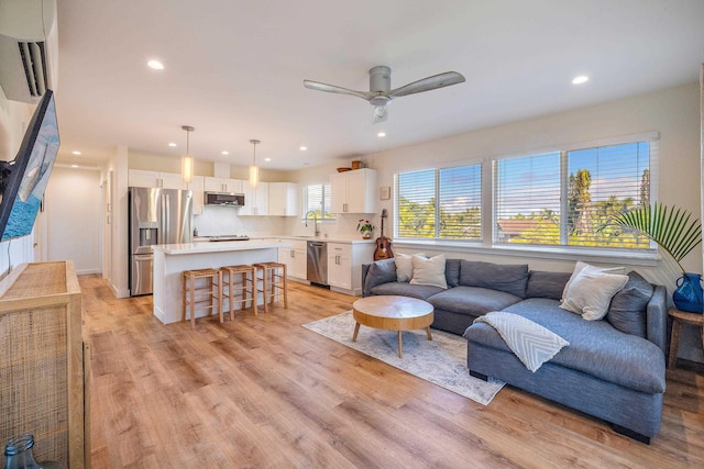 living room featuring sink, ceiling fan, and light hardwood / wood-style flooring