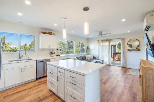 kitchen featuring sink, a wall mounted air conditioner, white cabinets, decorative light fixtures, and stainless steel dishwasher