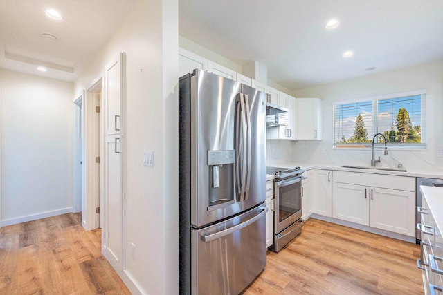 kitchen with sink, stainless steel appliances, white cabinets, and light wood-type flooring