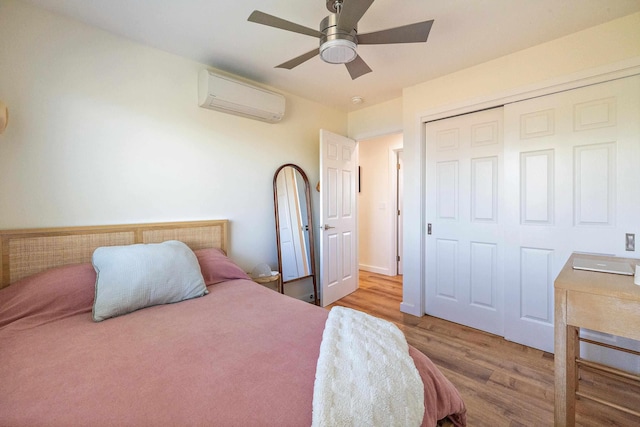 bedroom with a closet, an AC wall unit, ceiling fan, and light wood-type flooring