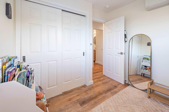 bedroom with a closet, an AC wall unit, and light wood-type flooring